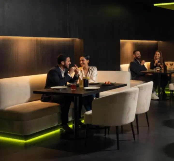 Modern, sötét belső tér lime-zöld fényekkel és elegáns, megterített asztalokkal a Moorvessában.